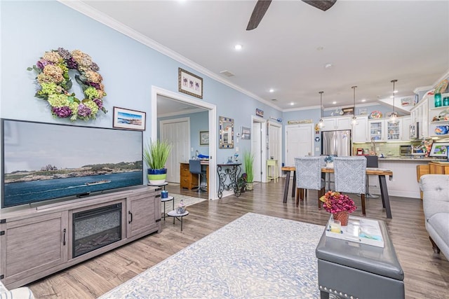 living room with ceiling fan, crown molding, and dark wood-type flooring