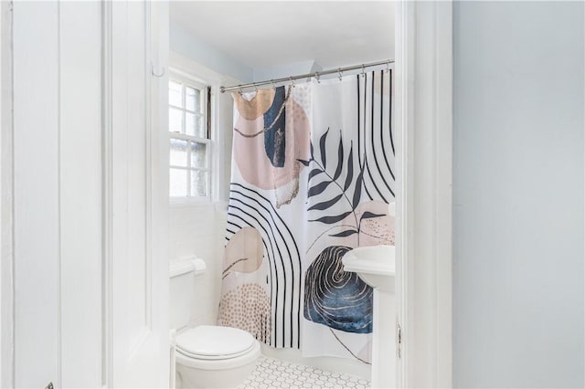 bathroom with a shower with shower curtain and toilet