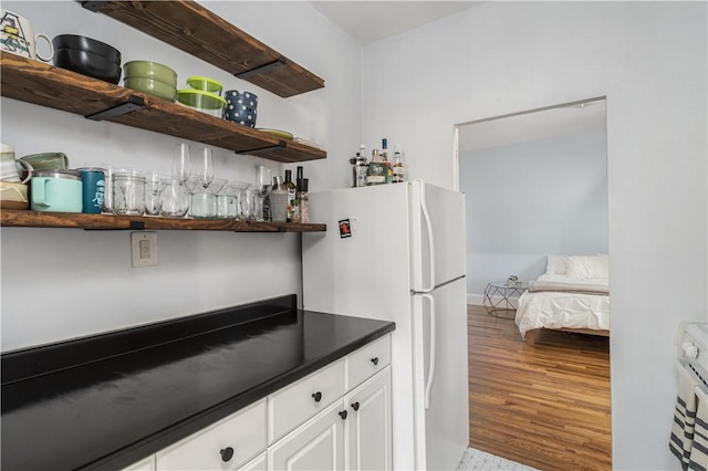 bar with white refrigerator, hardwood / wood-style flooring, and white cabinetry