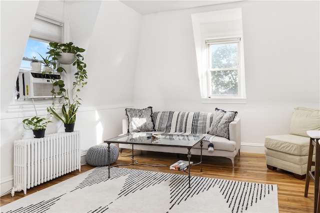 living area featuring wood-type flooring, radiator, and cooling unit