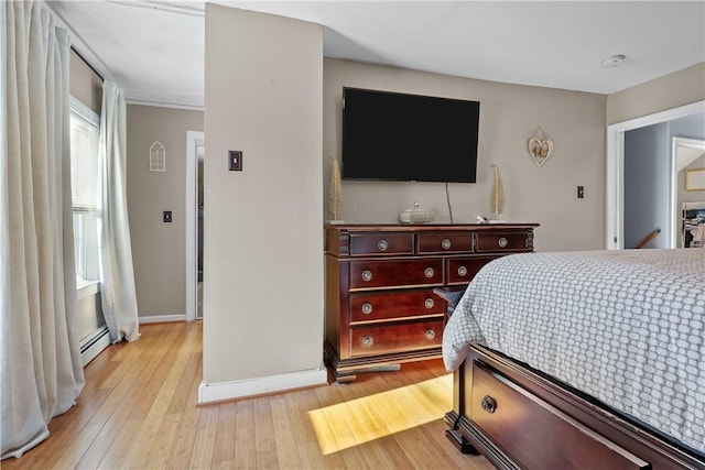 bedroom with light wood-type flooring and a baseboard heating unit