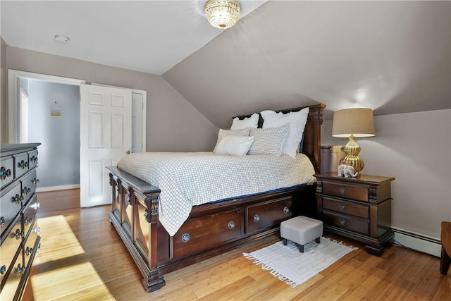 bedroom featuring light hardwood / wood-style floors, vaulted ceiling, and a baseboard radiator