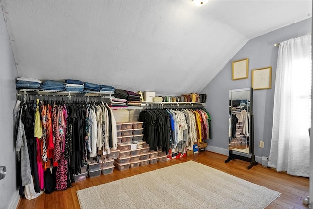 walk in closet with wood-type flooring and vaulted ceiling