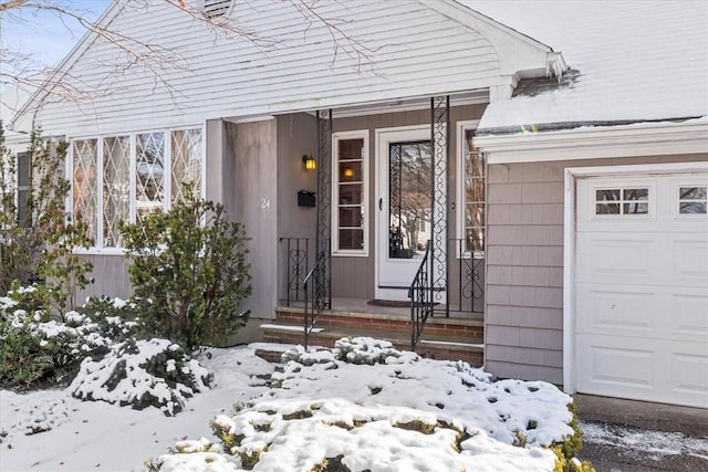 snow covered property entrance with a garage