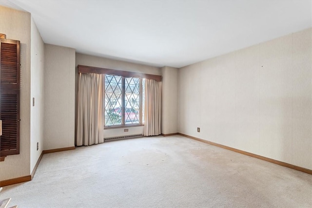 spare room featuring a baseboard radiator and light carpet