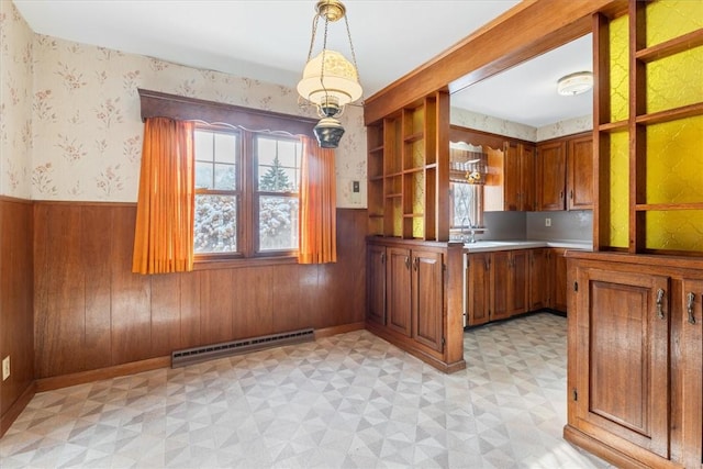 kitchen with a baseboard heating unit, wooden walls, and decorative light fixtures