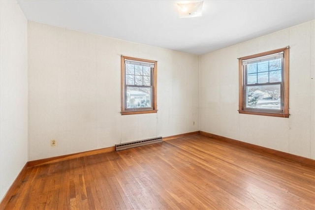 unfurnished room featuring baseboard heating, wood-type flooring, and a wealth of natural light