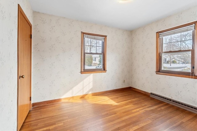 unfurnished room with a baseboard radiator and light hardwood / wood-style floors