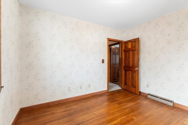 empty room featuring a baseboard radiator and hardwood / wood-style floors