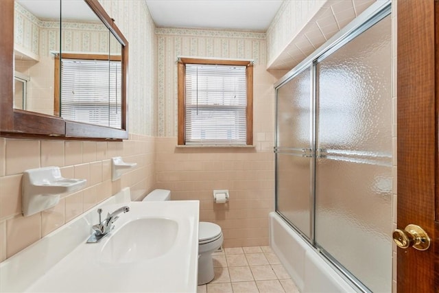 full bathroom featuring combined bath / shower with glass door, tile walls, vanity, tile patterned floors, and toilet