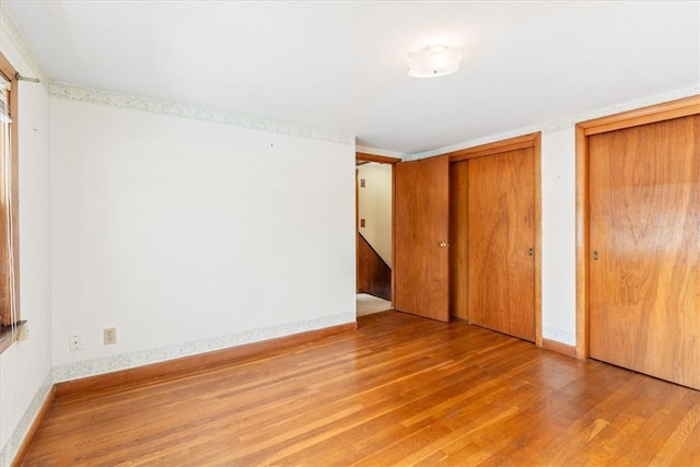 unfurnished bedroom with multiple closets and light wood-type flooring