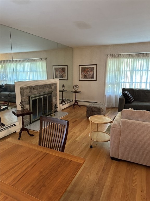 living room featuring hardwood / wood-style flooring, a baseboard radiator, and a stone fireplace