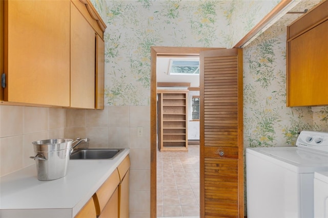 clothes washing area featuring sink, cabinets, washer / dryer, and light tile patterned floors