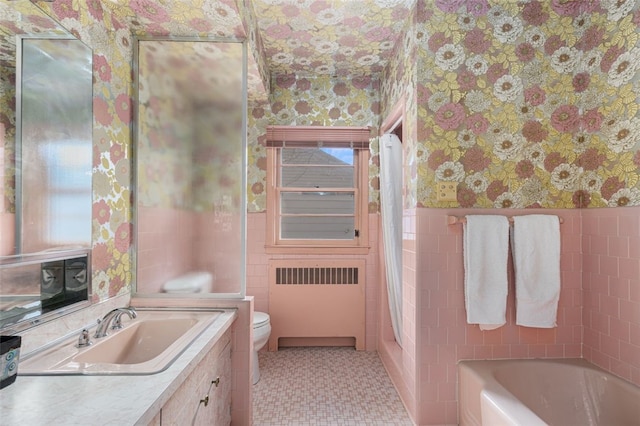 bathroom with toilet, vanity, radiator heating unit, and a bathtub