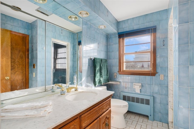 bathroom featuring tile walls, toilet, radiator, and vanity