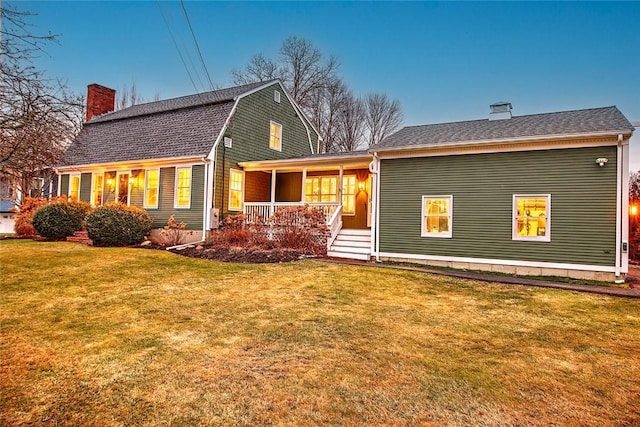 back of property with covered porch and a lawn