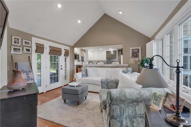 living room featuring high vaulted ceiling, light wood-type flooring, and sink