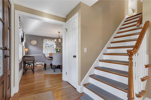 foyer entrance featuring light wood-type flooring, crown molding, and a chandelier