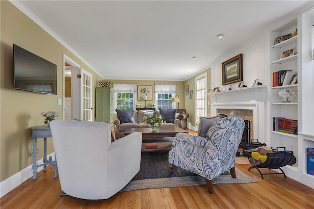 living room with a high end fireplace, hardwood / wood-style floors, a wealth of natural light, and ornamental molding