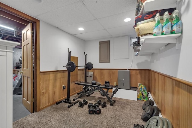 exercise room featuring a paneled ceiling, carpet, and electric panel