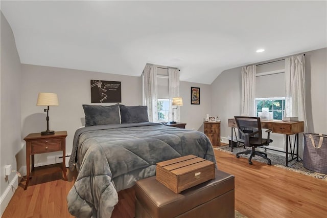 bedroom with lofted ceiling, wood-type flooring, and multiple windows