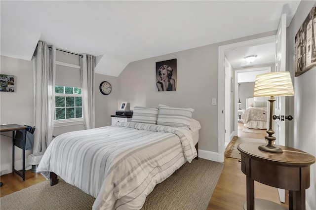 bedroom featuring light wood-type flooring and vaulted ceiling