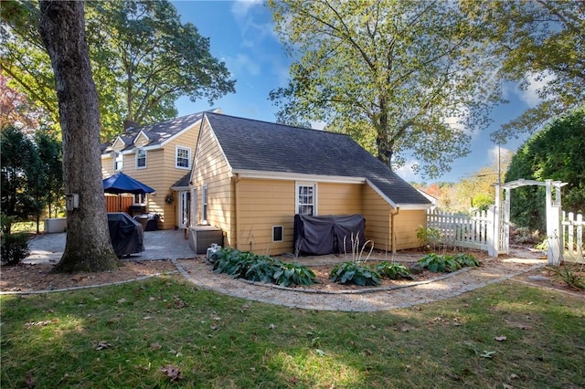 rear view of property with a lawn and a patio