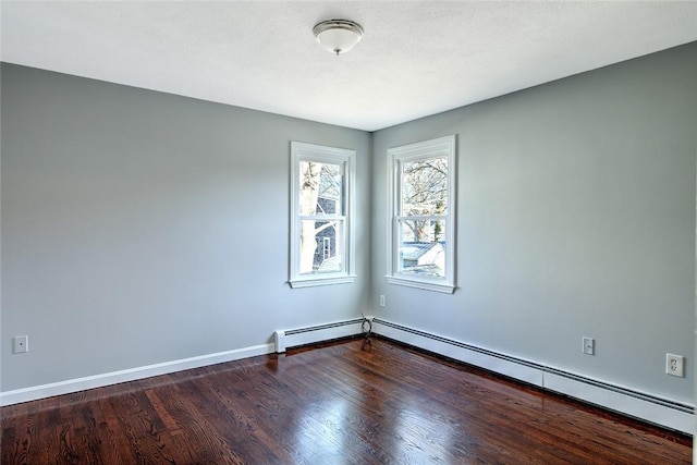 spare room with dark wood-type flooring and a baseboard heating unit