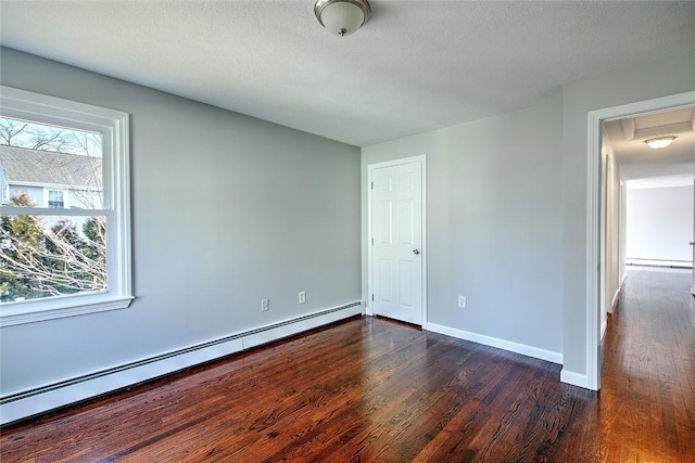 empty room featuring a textured ceiling, a baseboard radiator, and dark hardwood / wood-style floors