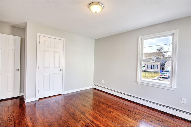 unfurnished bedroom with baseboard heating and dark wood-type flooring