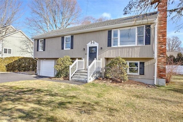 raised ranch with a front lawn and a garage