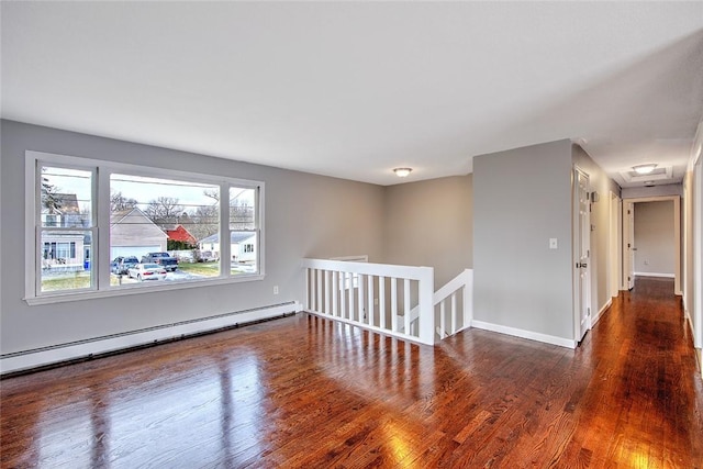 unfurnished room featuring a baseboard heating unit and dark wood-type flooring