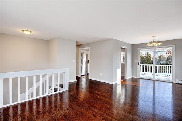 unfurnished room with a notable chandelier, dark hardwood / wood-style flooring, and a baseboard heating unit