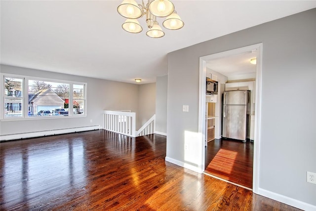 spare room with baseboard heating, an inviting chandelier, and hardwood / wood-style floors