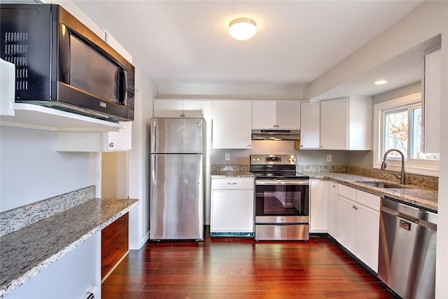 kitchen featuring appliances with stainless steel finishes, white cabinetry, light stone counters, and sink