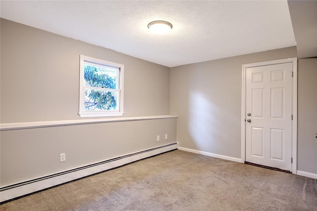 carpeted empty room featuring a baseboard heating unit and a textured ceiling