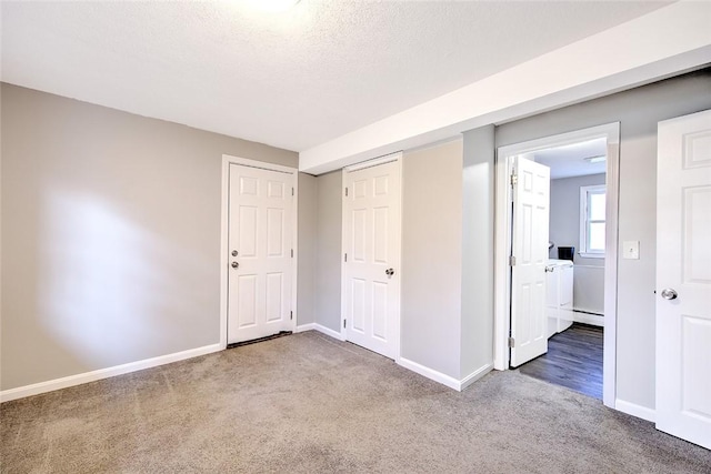 unfurnished bedroom featuring a textured ceiling, a closet, carpet floors, and a baseboard heating unit