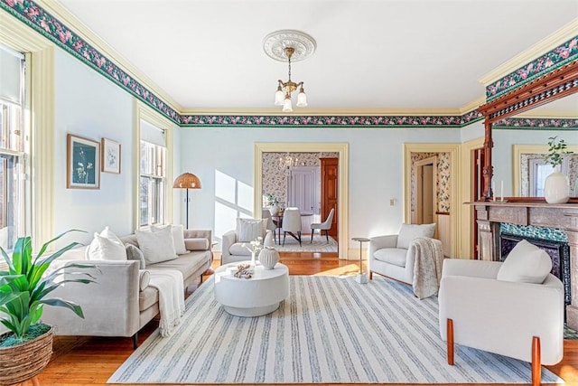 living room featuring a fireplace, crown molding, hardwood / wood-style flooring, and a notable chandelier