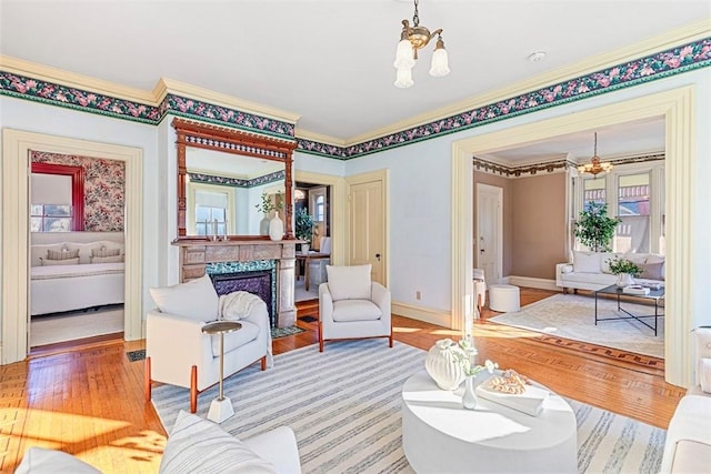 living room featuring a notable chandelier, crown molding, a fireplace, and hardwood / wood-style flooring