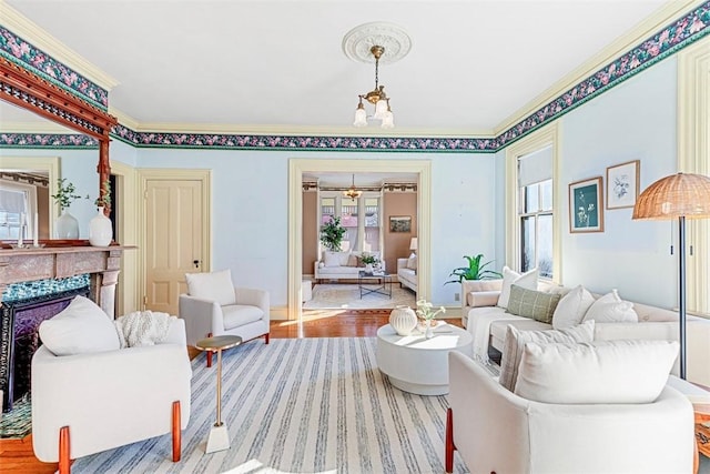 living room with a fireplace, a notable chandelier, light hardwood / wood-style floors, and ornamental molding