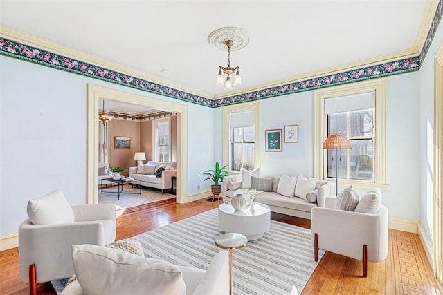 living room with an inviting chandelier, ornamental molding, and hardwood / wood-style floors