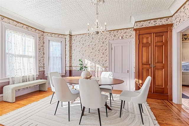 dining space with crown molding, a notable chandelier, and light hardwood / wood-style flooring