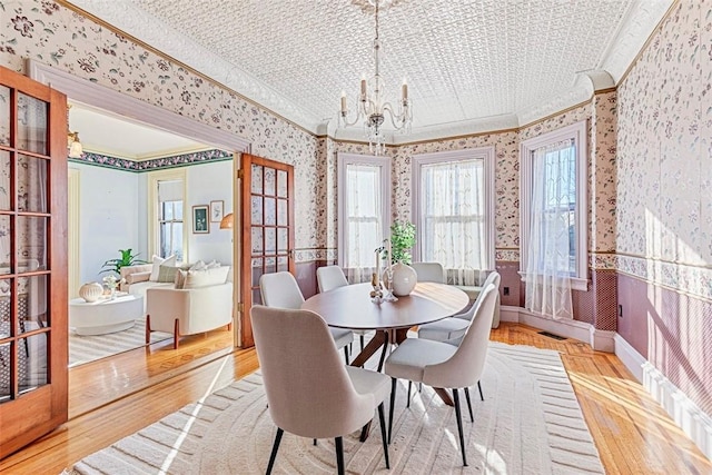 dining room with ornamental molding, light hardwood / wood-style floors, and a notable chandelier