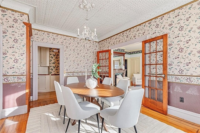 dining area with light wood-type flooring, ornamental molding, and a chandelier