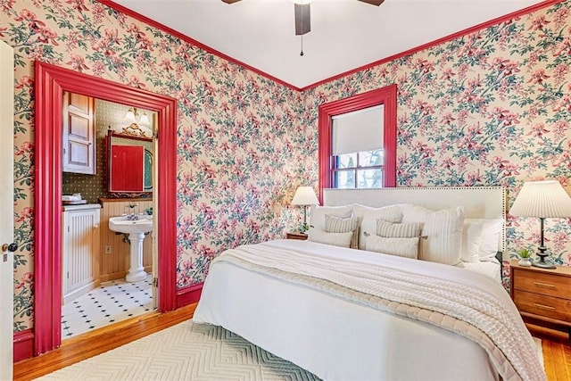 bedroom with wood-type flooring, ensuite bathroom, ceiling fan, and crown molding