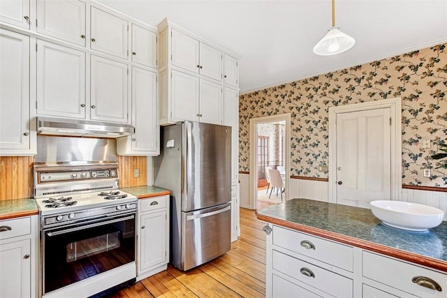 kitchen featuring white cabinetry, white stove, and stainless steel refrigerator