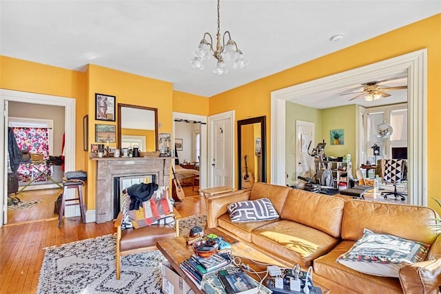 living room with ceiling fan with notable chandelier and light wood-type flooring