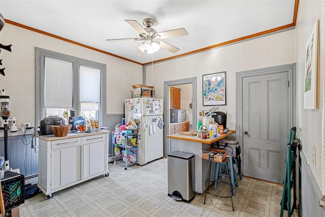 kitchen with white fridge, ceiling fan, ornamental molding, a baseboard heating unit, and white cabinets