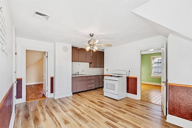 kitchen featuring sink, white gas stove, dark brown cabinets, and light hardwood / wood-style flooring