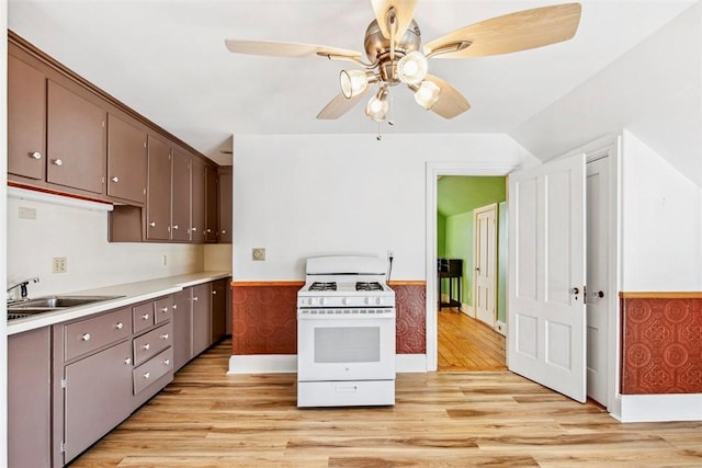 kitchen with sink, white range with gas cooktop, light hardwood / wood-style floors, ceiling fan, and dark brown cabinetry